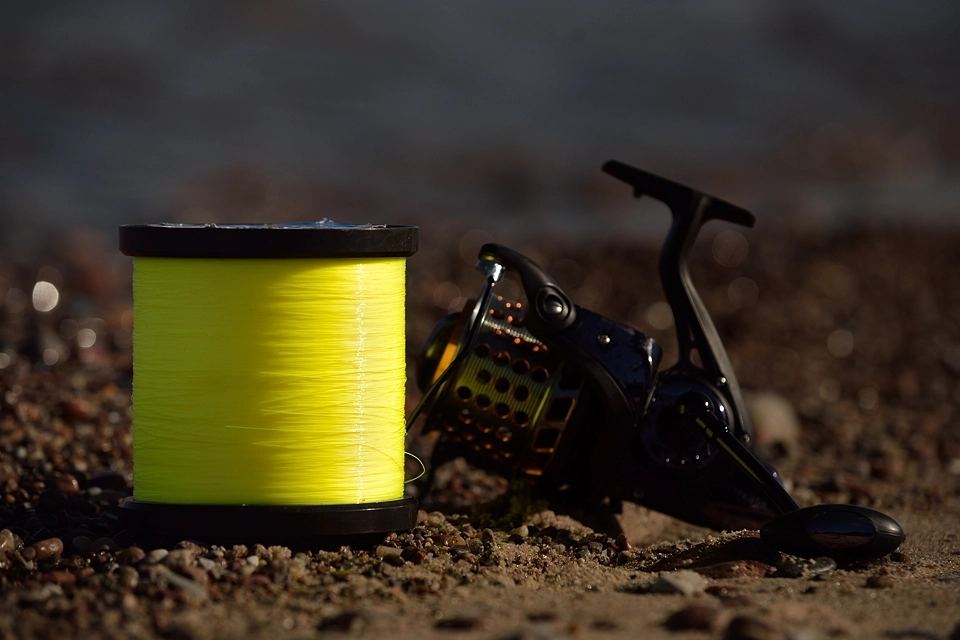 Żyłka na dużej szpuli postawiona na plaży obok kołowrotka morskiego