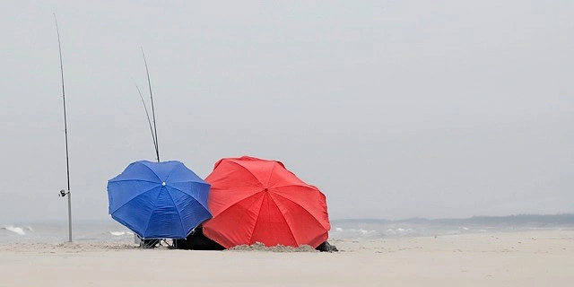 plaża nad Bałtykiem i parasolki chroniące wędkarzy przed wiatrem
